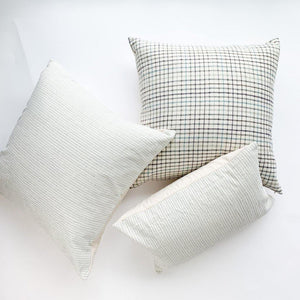 A soft ivory pillow featuring a green and indigo checkered weave. Handcrafted by Ginger Sparrow, a modern home decor brand.