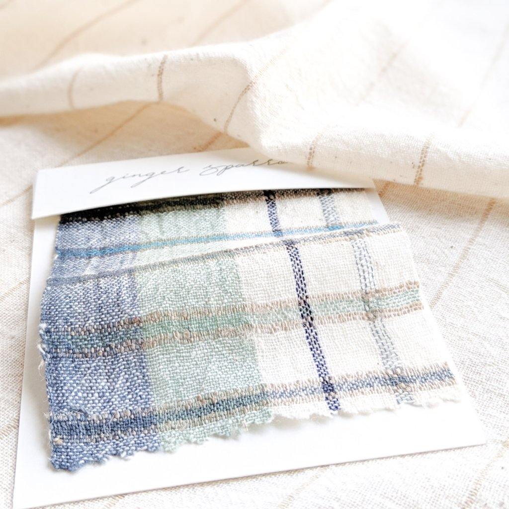 Handwoven Textile by Ginger Sparrow, a modern home decor brand. Featuring a soft ivory ground with a green and indigo striped weave. Light and airy its perfect for #windowshades #drapes #livingroomdecor #bedroomideas