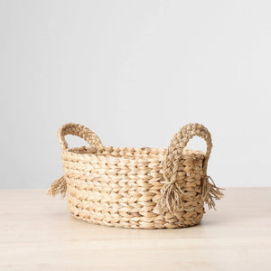 Closeup view of a dried water grass basket in a buttery golden hue, finished with braided handles. Perfect to stash fruits, towels, candles etc.  