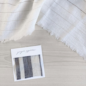 A soft ivory and charcoal striped handwoven cotton pillow . Handcrafted by Ginger Sparrow, a modern home decor brand.